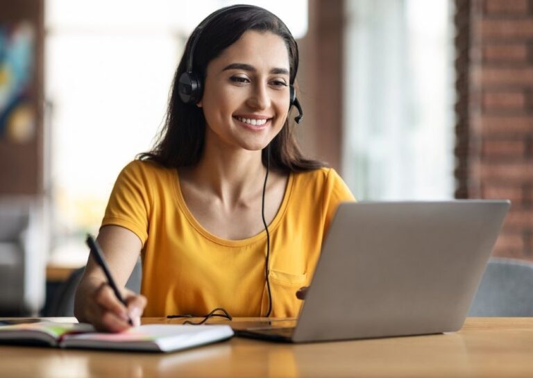 Ein Foto von einer Frau, die vor einem Laptop sitzt und an einem online Kurs teilnimmt.