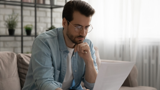 Ein Foto von einem Mann, der ein Blatt Papier in der Hand hält und nachdenkt.