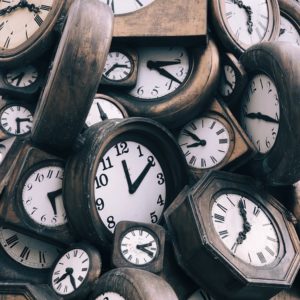 Arbeitszeiten erfassen - E-Learning - Viele Uhren mit Holzumrahmung liegen auf einem Haufen.