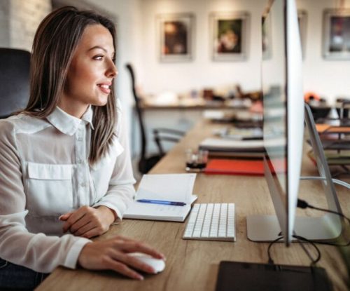 Eine Frau schaut auf ihren Computerbildschirm und lächelt.