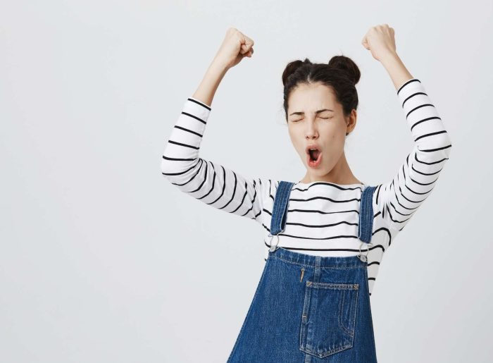 A young woman in striped shirt and dungarees is happy about the translations and accessible information from capito.