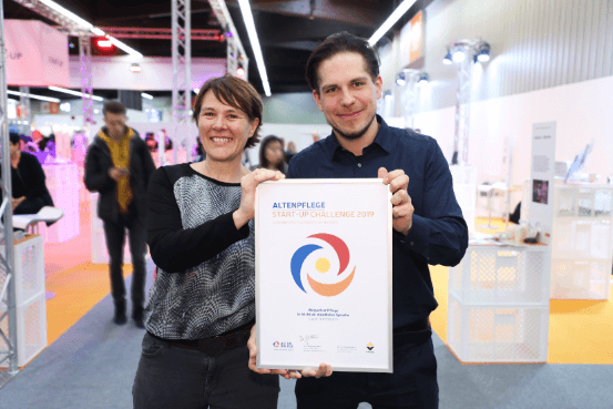 Foto von Sabrina Weyh und Michael Kaier mit ihrer Gewinner-Urkunde der Altenpflege Start-Up Challenge.