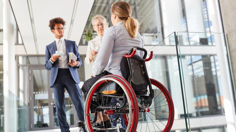 Frau im Rollstuhl und zwei Männer besprechen capito Projekt mit Sozialbetriebe